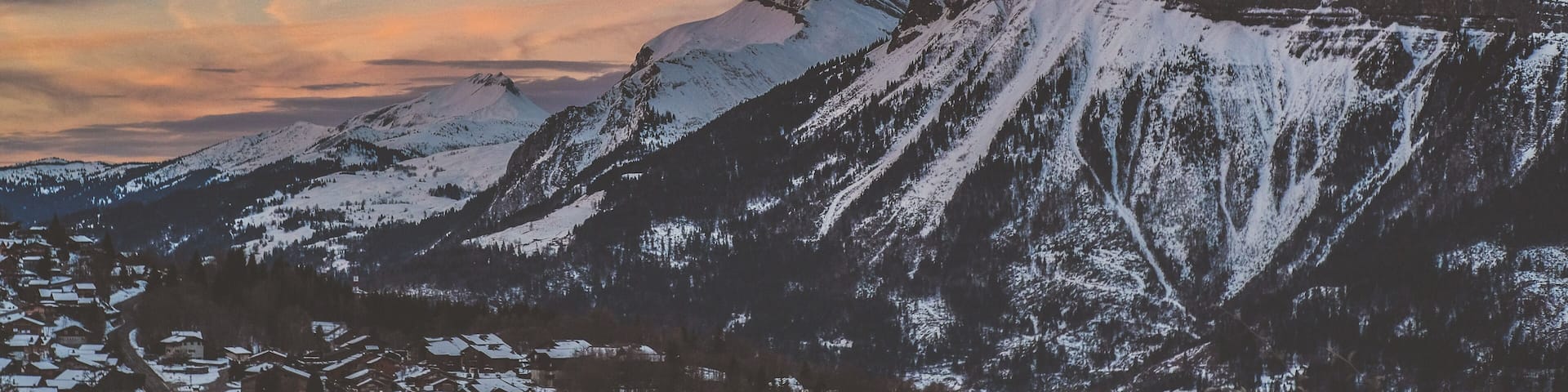 A snow-covered mountain range with a small village at its base.