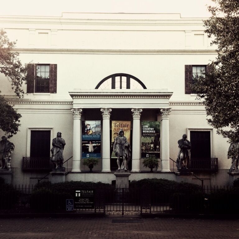 A building with classical architecture, featuring columns and statues on the facade.