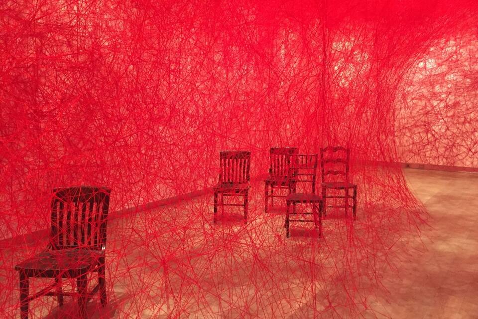 Ein Zimmer mit roten Netzhängen und vier Holzstühlen.