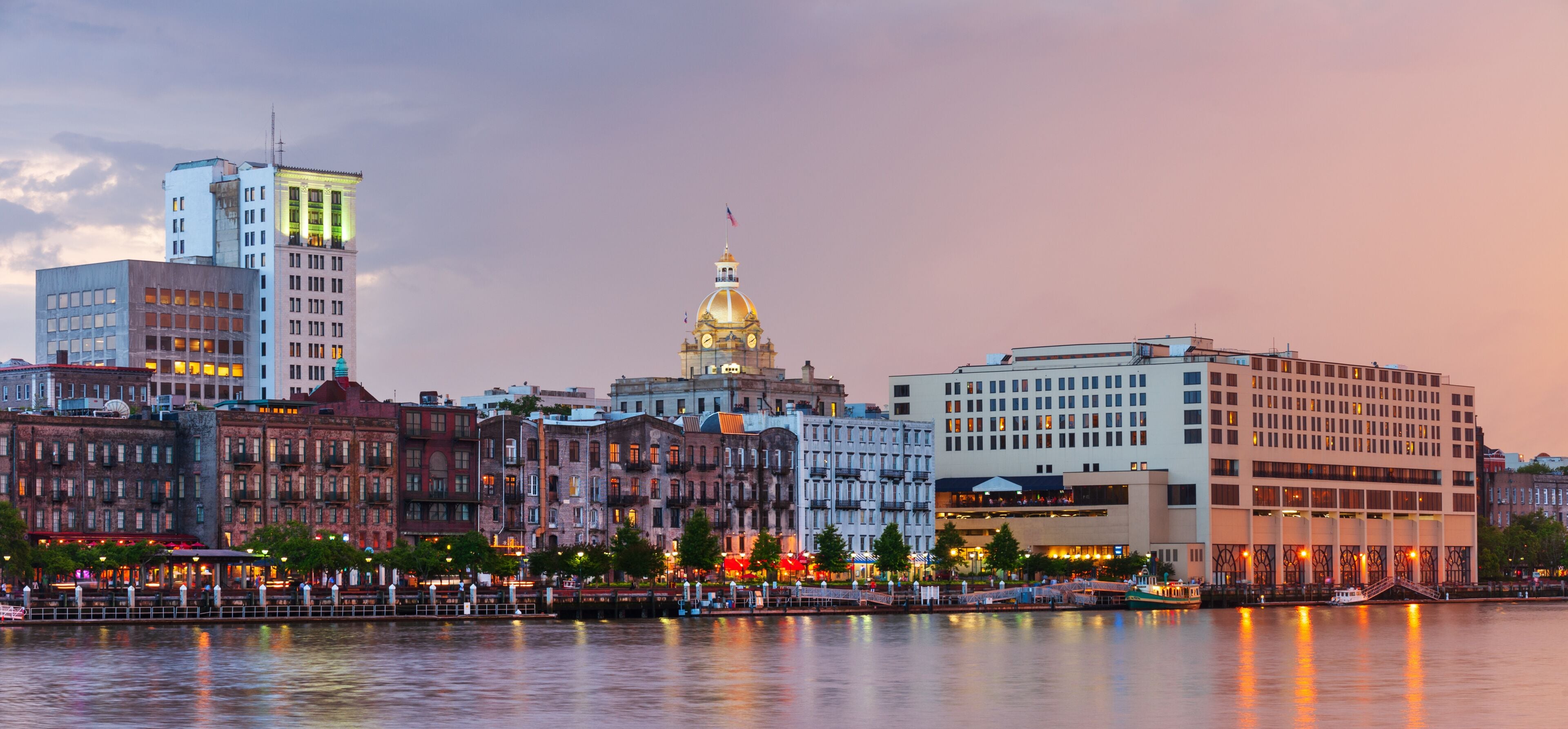 A waterfront cityscape with historic buildings, a prominent golden-domed structure, and a river reflecting the city lights.