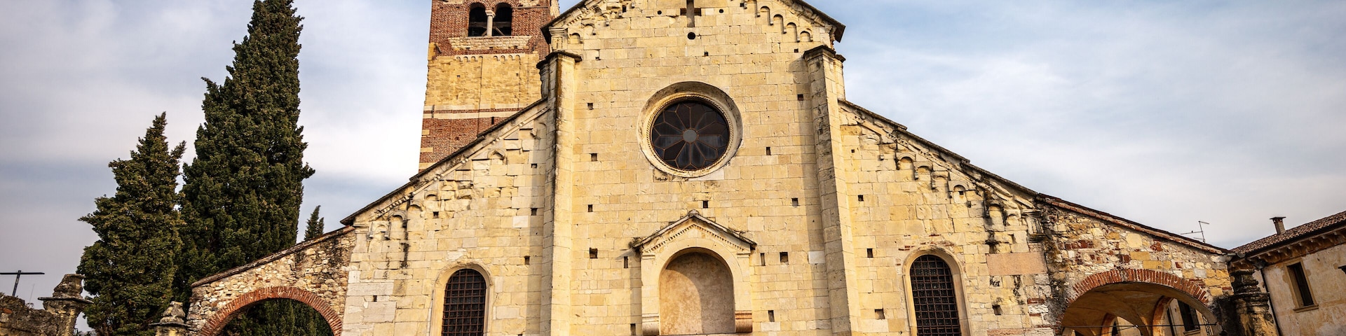 Una iglesia histórica con una torre de campanas, ventanas de arco y un ventanal circular central.