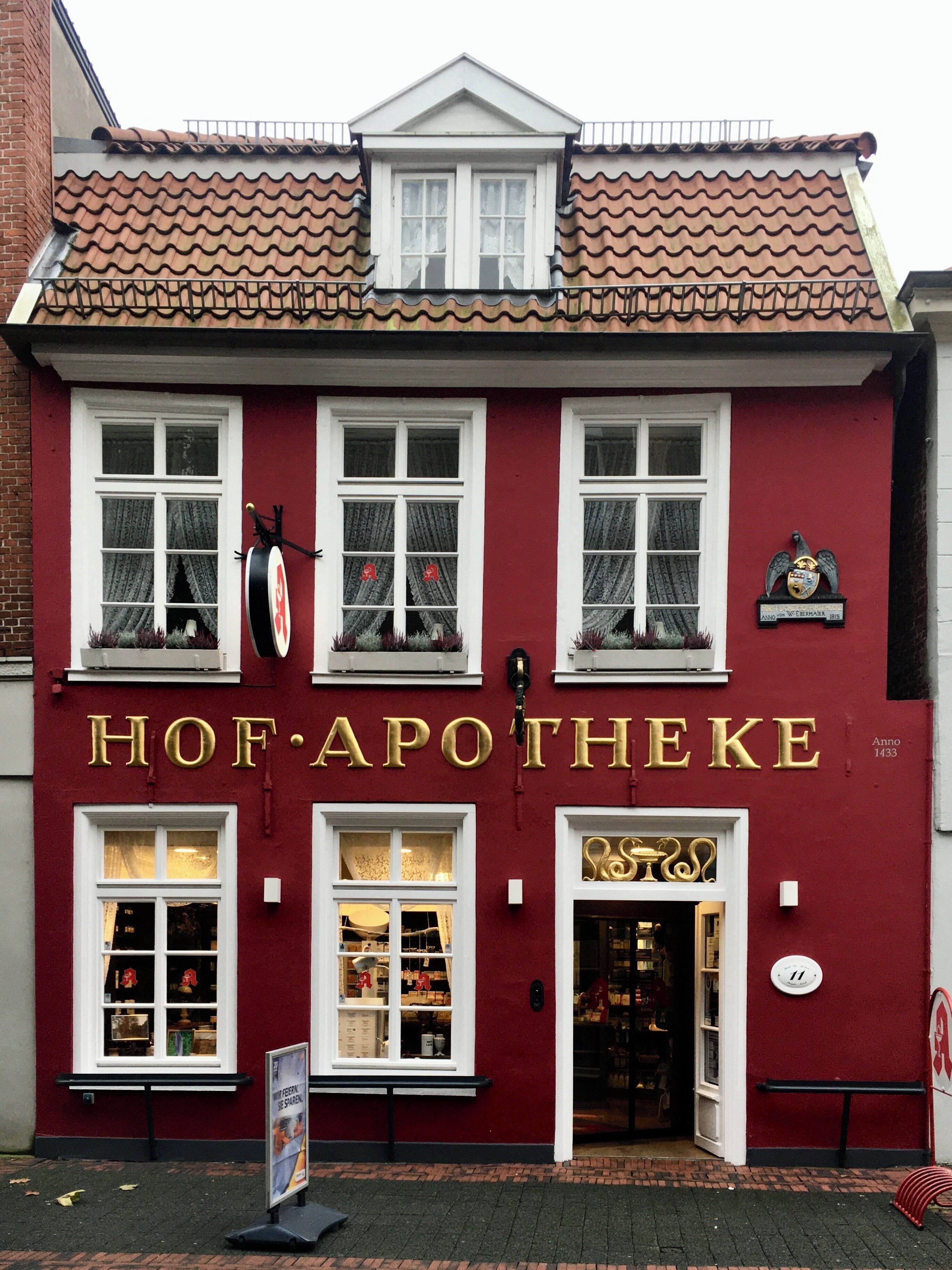 A red building with gold lettering reading "Hof Apotheke" and a sign indicating the year 1433.