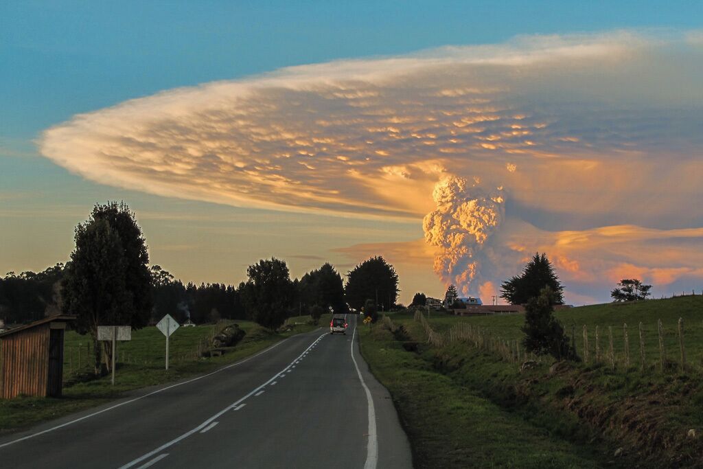 A rural road with a sunset and a large cloud formation.
