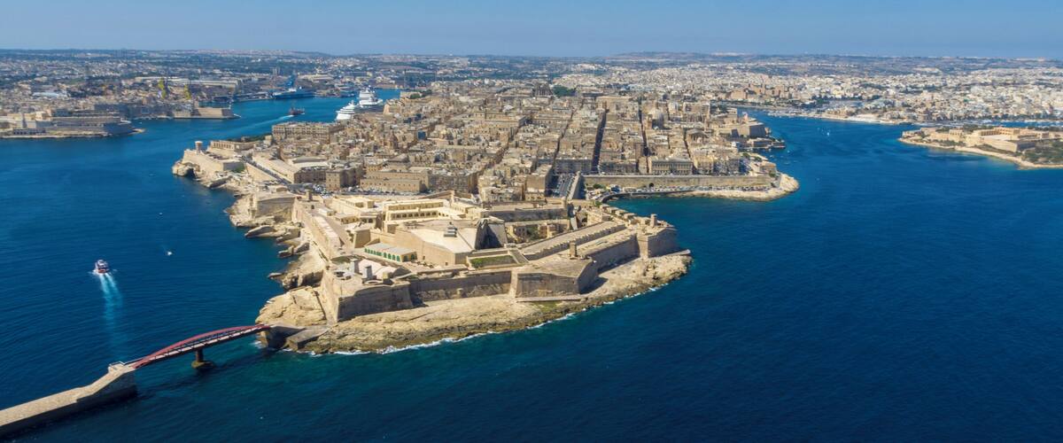 An aerial view of a fortified city with a prominent castle on an island, surrounded by water.