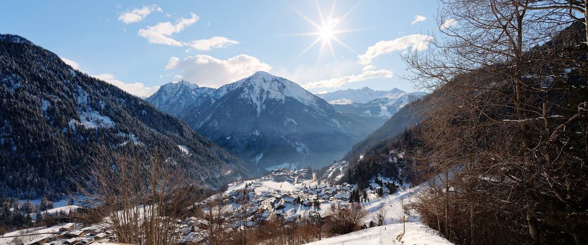Un paysage montagneux enneigé, avec un village niché au fond de la vallée.