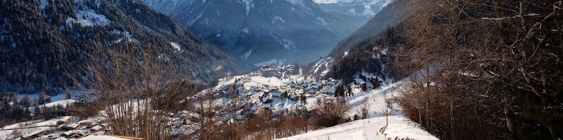 A snow-covered mountain landscape with a village nestled in the valley.