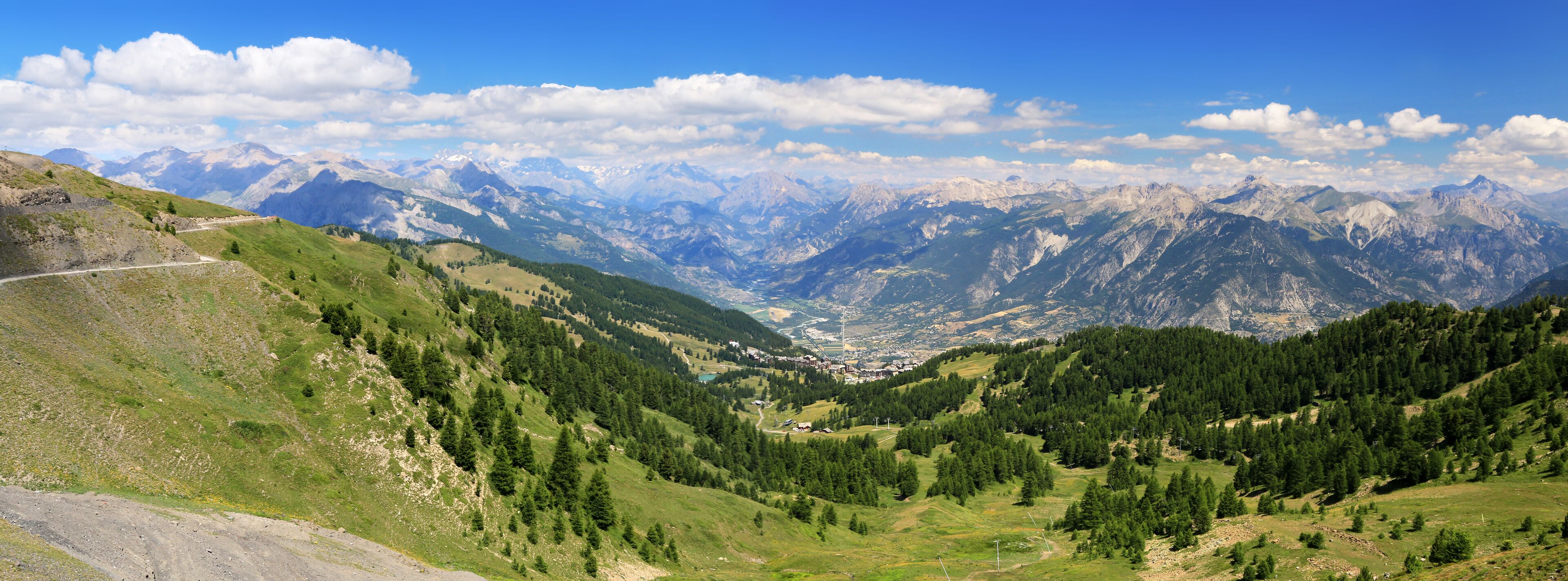 A mountainous landscape with a valley, a road, and a town nestled among the hills.
