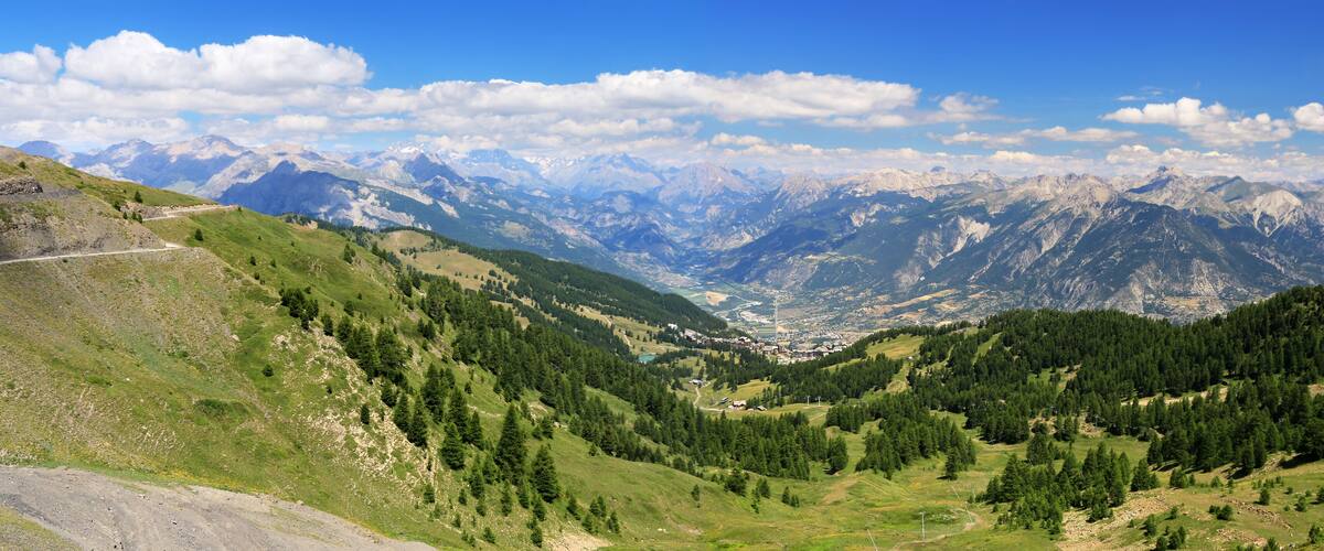 A mountainous landscape with a valley, a road, and a town nestled among the hills.