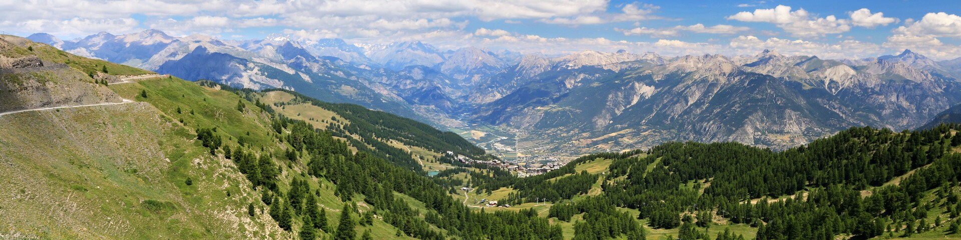 A mountainous landscape with a valley, a road, and a town nestled among the hills.
