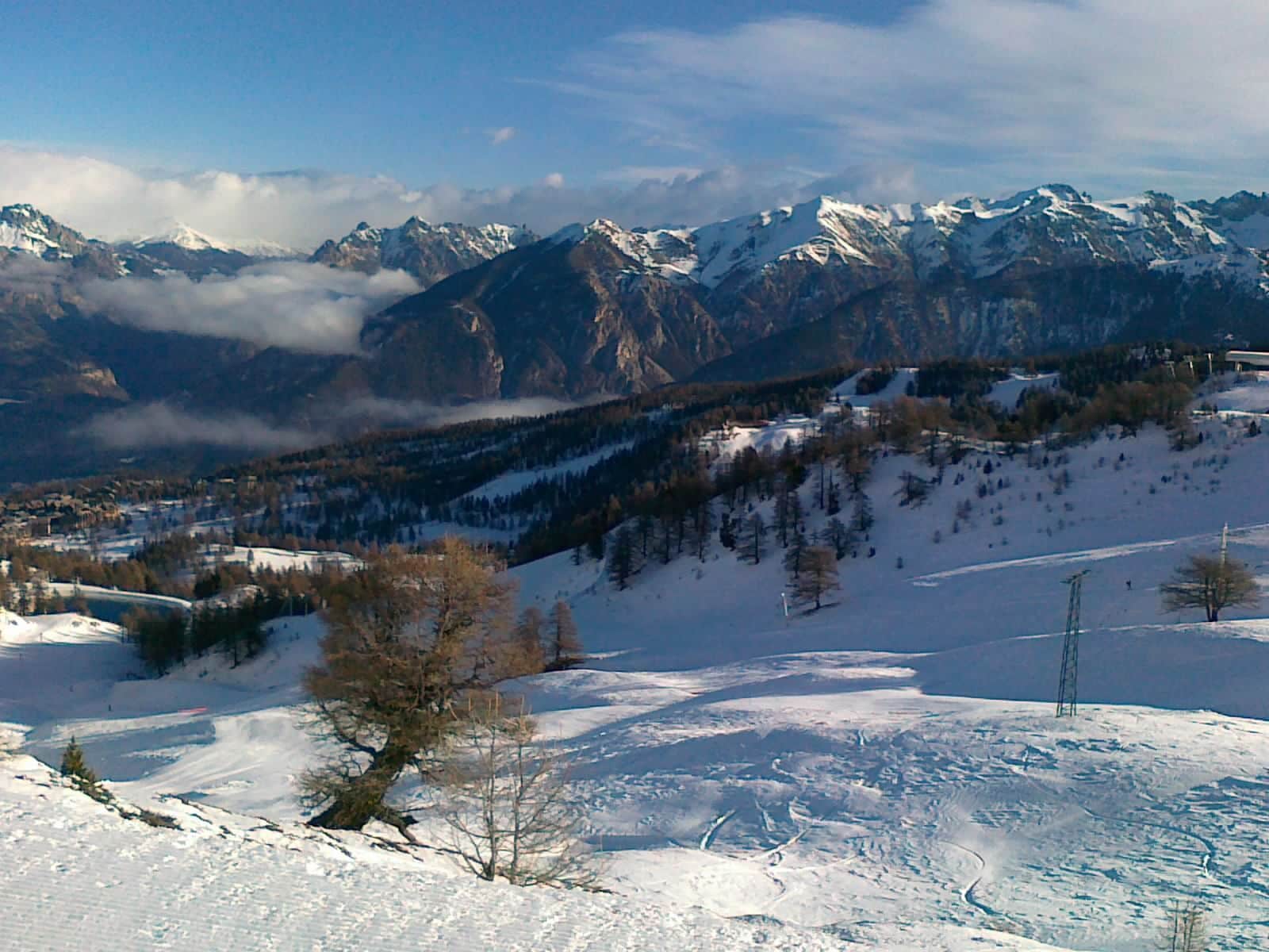 A snow-covered mountain landscape with a ski resort and a clear sky.