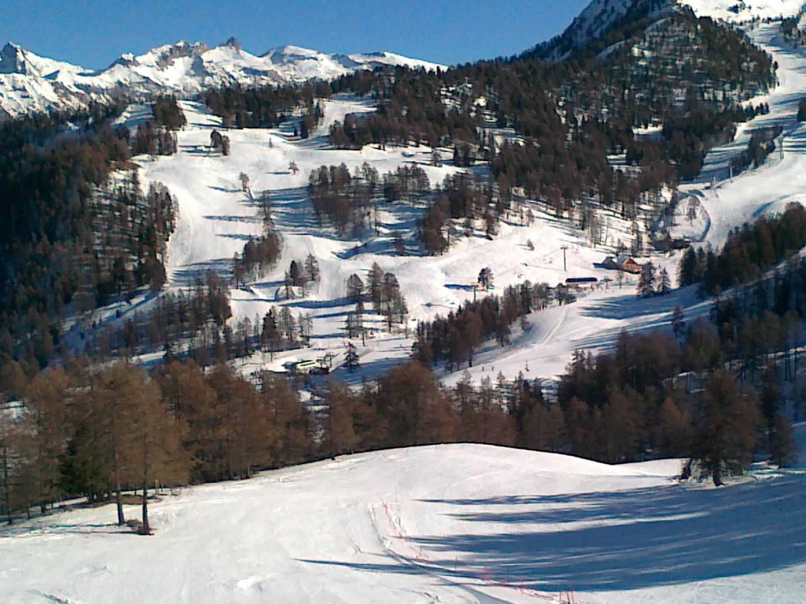 A snow-covered mountain landscape with ski slopes and a ski lift.