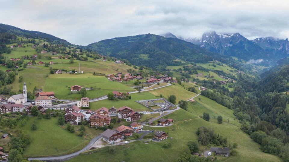 A mountainous village with traditional houses, a church, and a winding road.