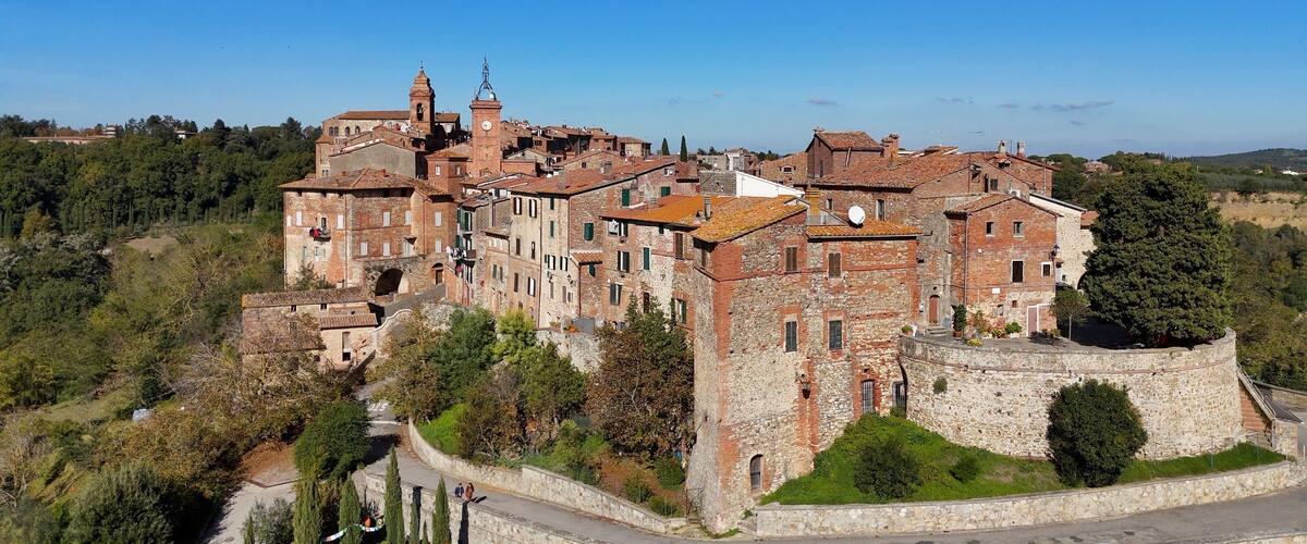 A historic town with a prominent church and castle-like structure surrounded by greenery and hills.