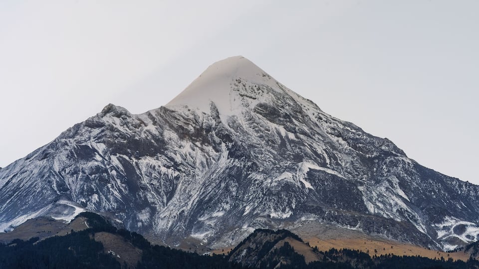 A snow-covered mountain with a sharp peak and rugged terrain.