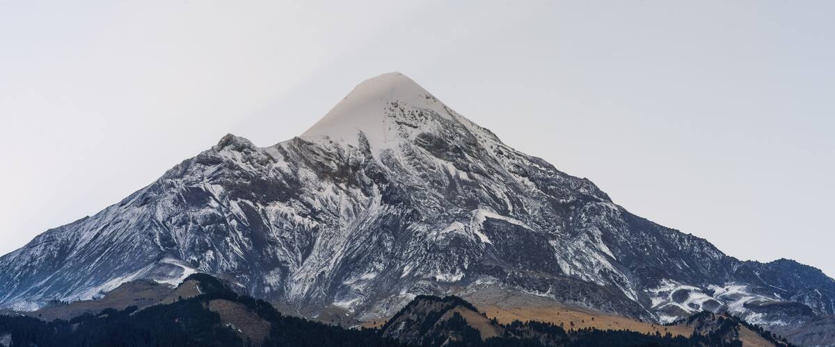 A snow-covered mountain with a sharp peak and rugged terrain.