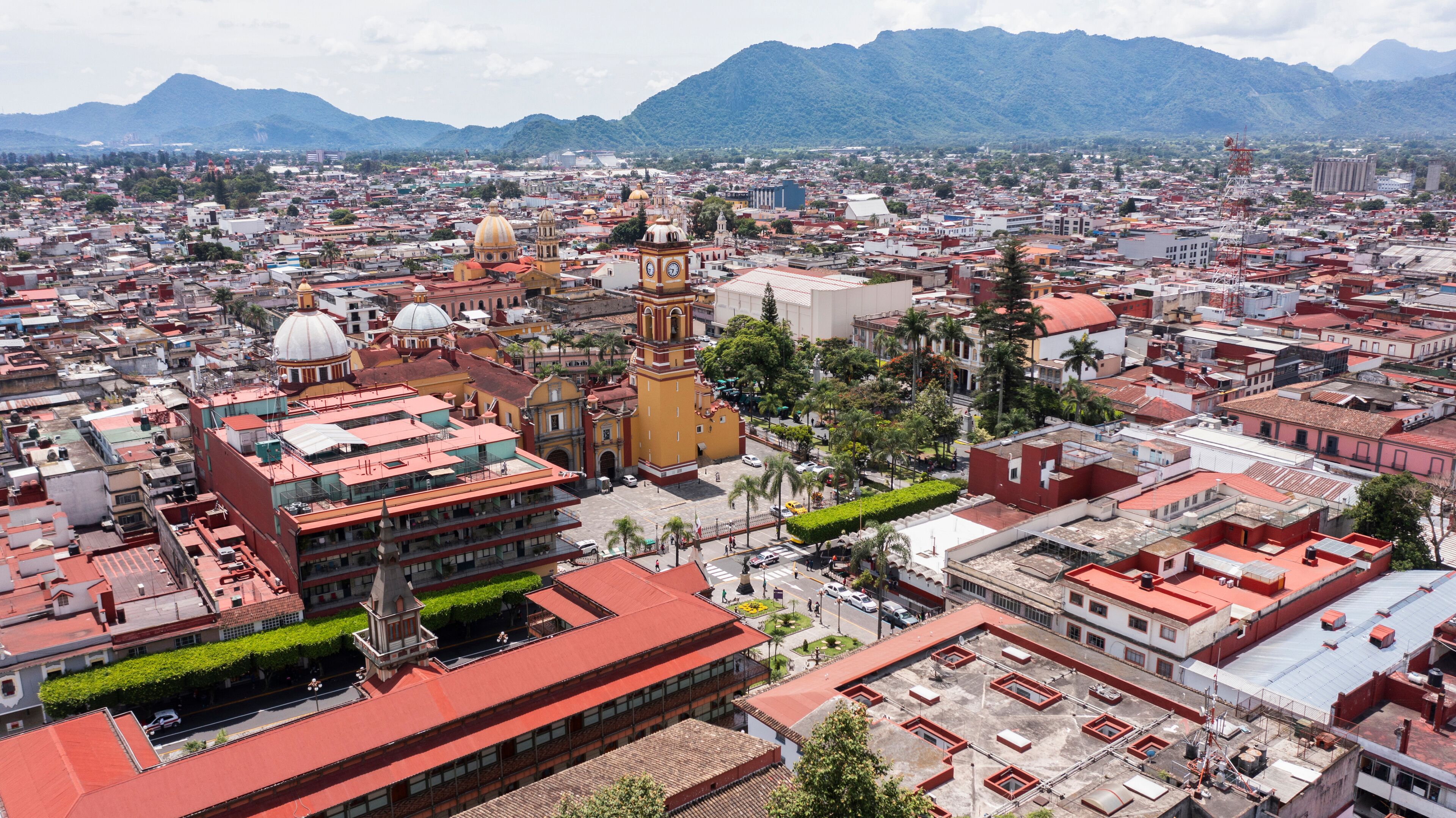 Orizaba, Veracruz, Mexico - July 14, 2022: Surrounded by mountains, cloudy sun shines on the historic core and churches of downtown Orizaba.
