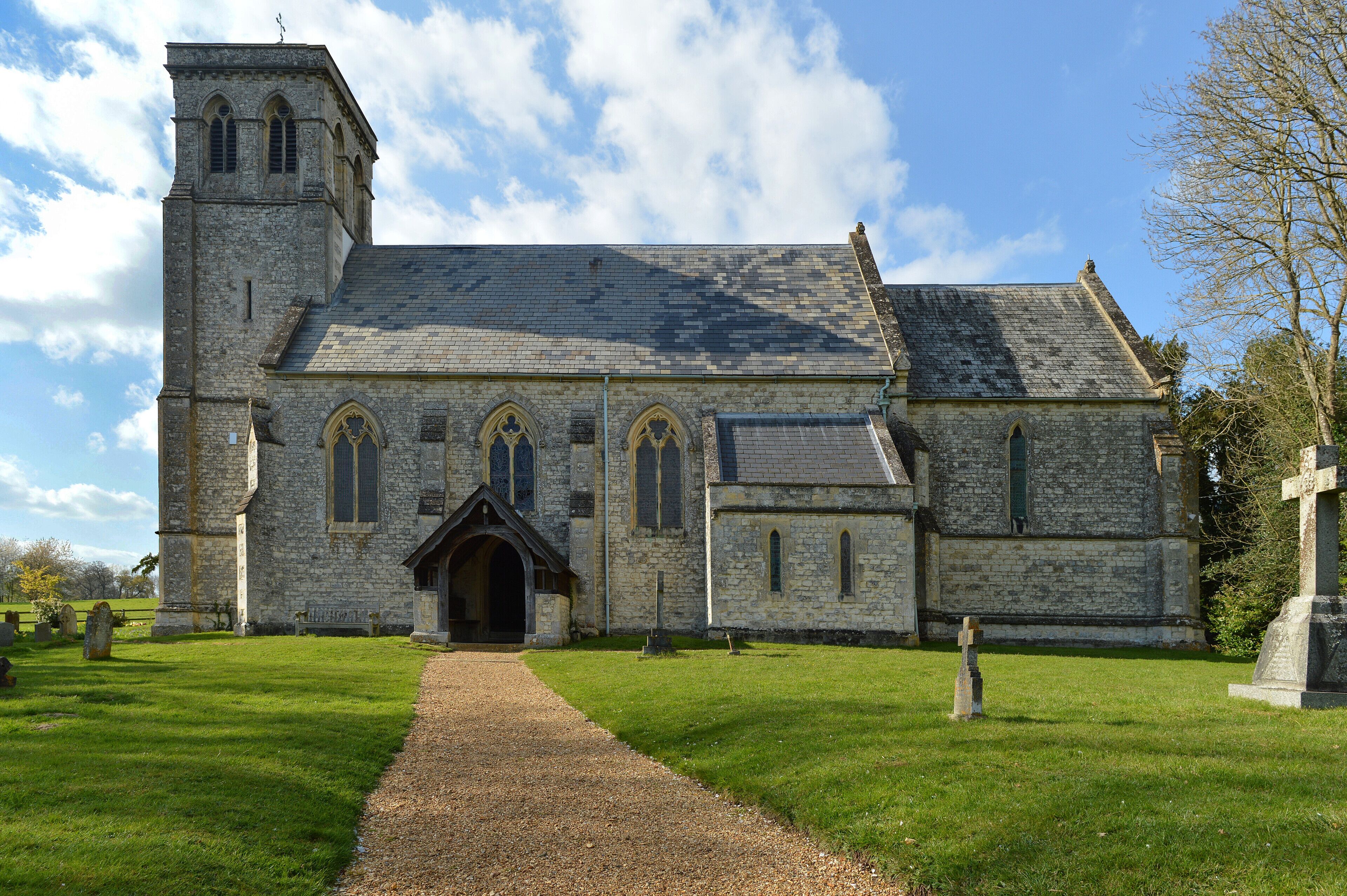 A stone church with a tower, arched windows, and a graveyard.