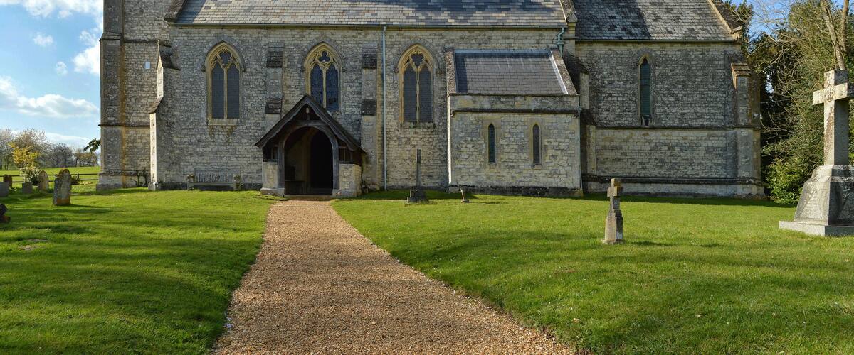 A stone church with a tower, arched windows, and a graveyard.