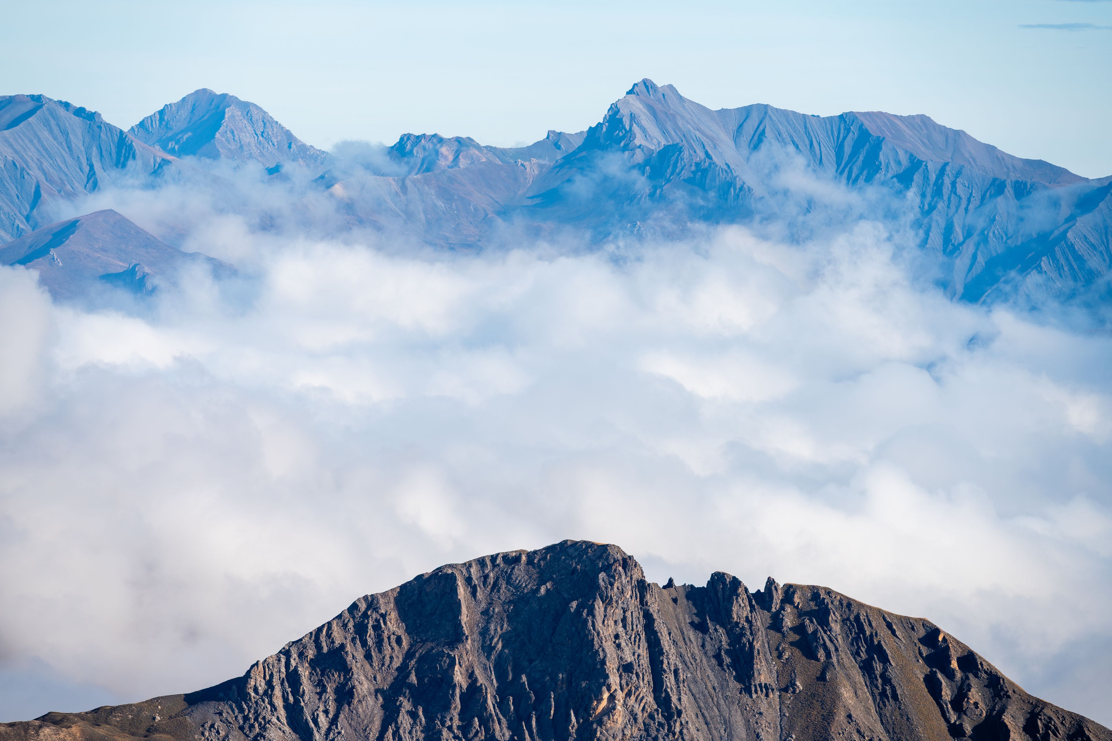 Panoramic mountain peaks emerging above a sea of clouds viewed from Col du Galibier, French Alps