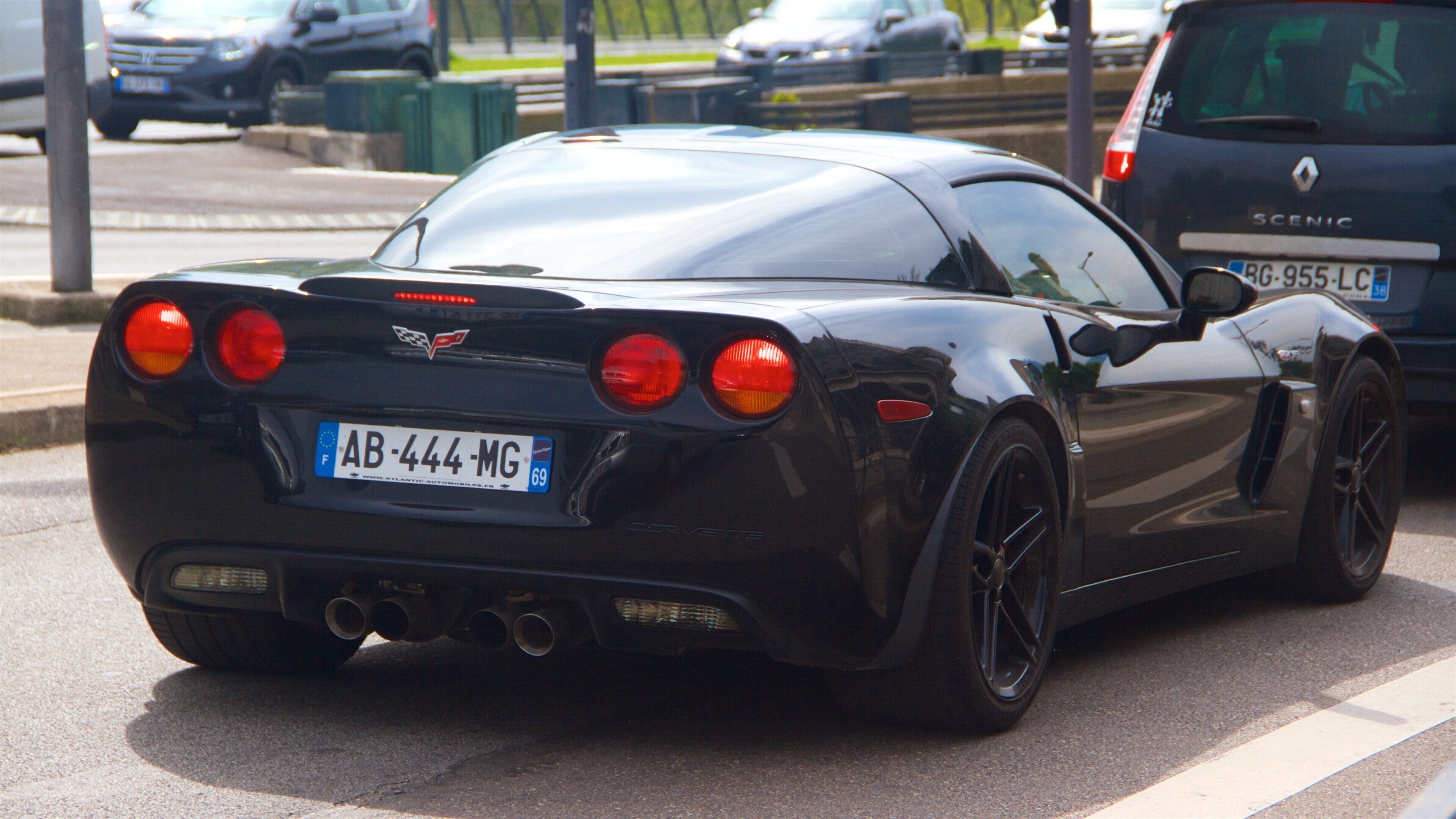 A black sports car with a European license plate AB-444-MG parked on a street.