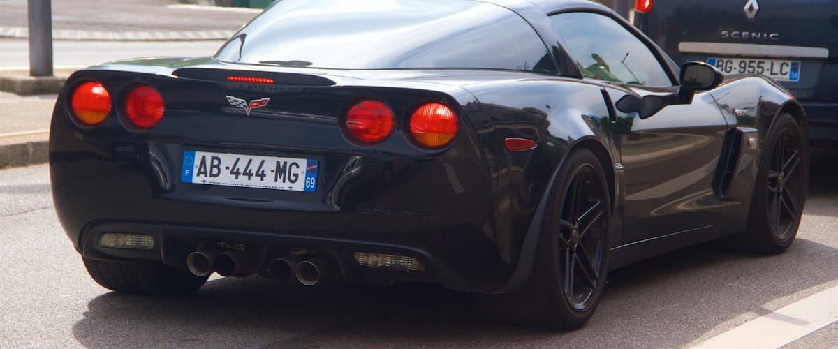 A black sports car with a European license plate AB-444-MG parked on a street.