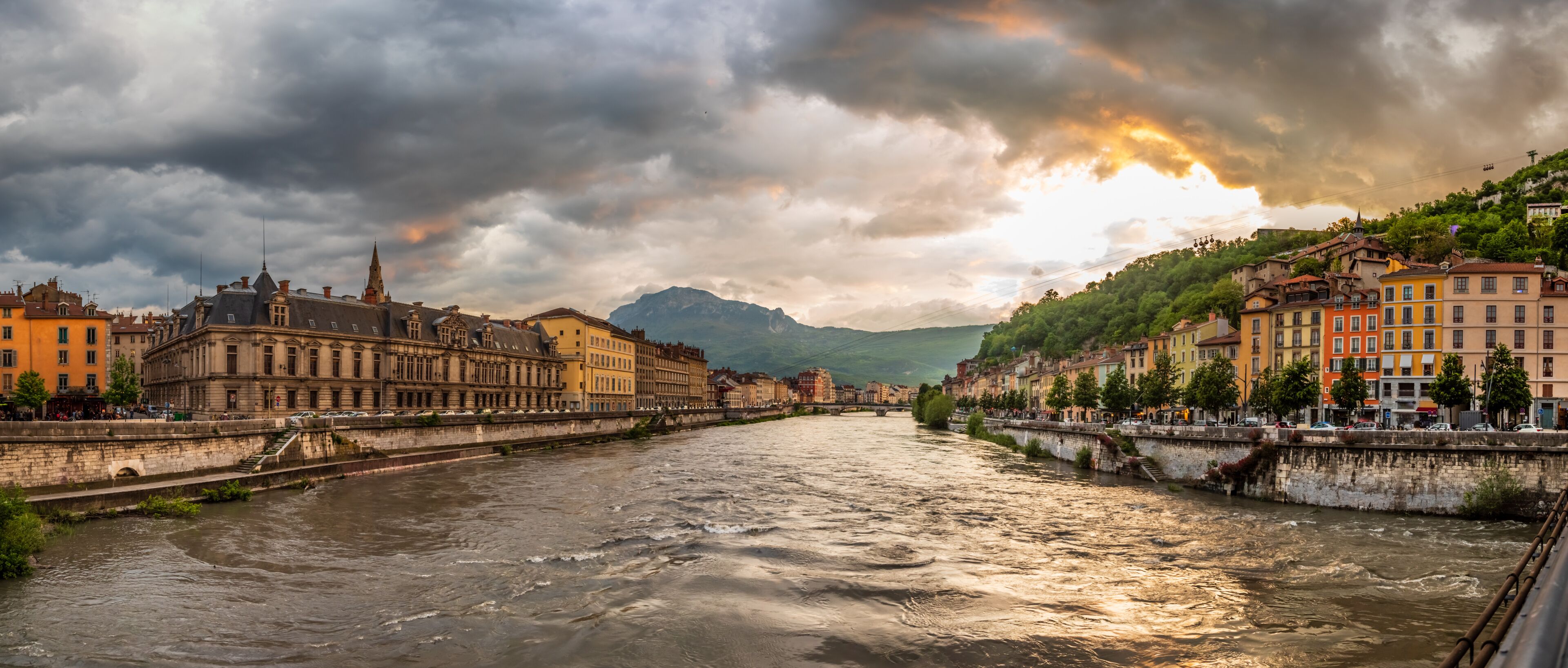Panorama with a dramatic sunset looking down the Isere river towards the old section of Grenoble France
