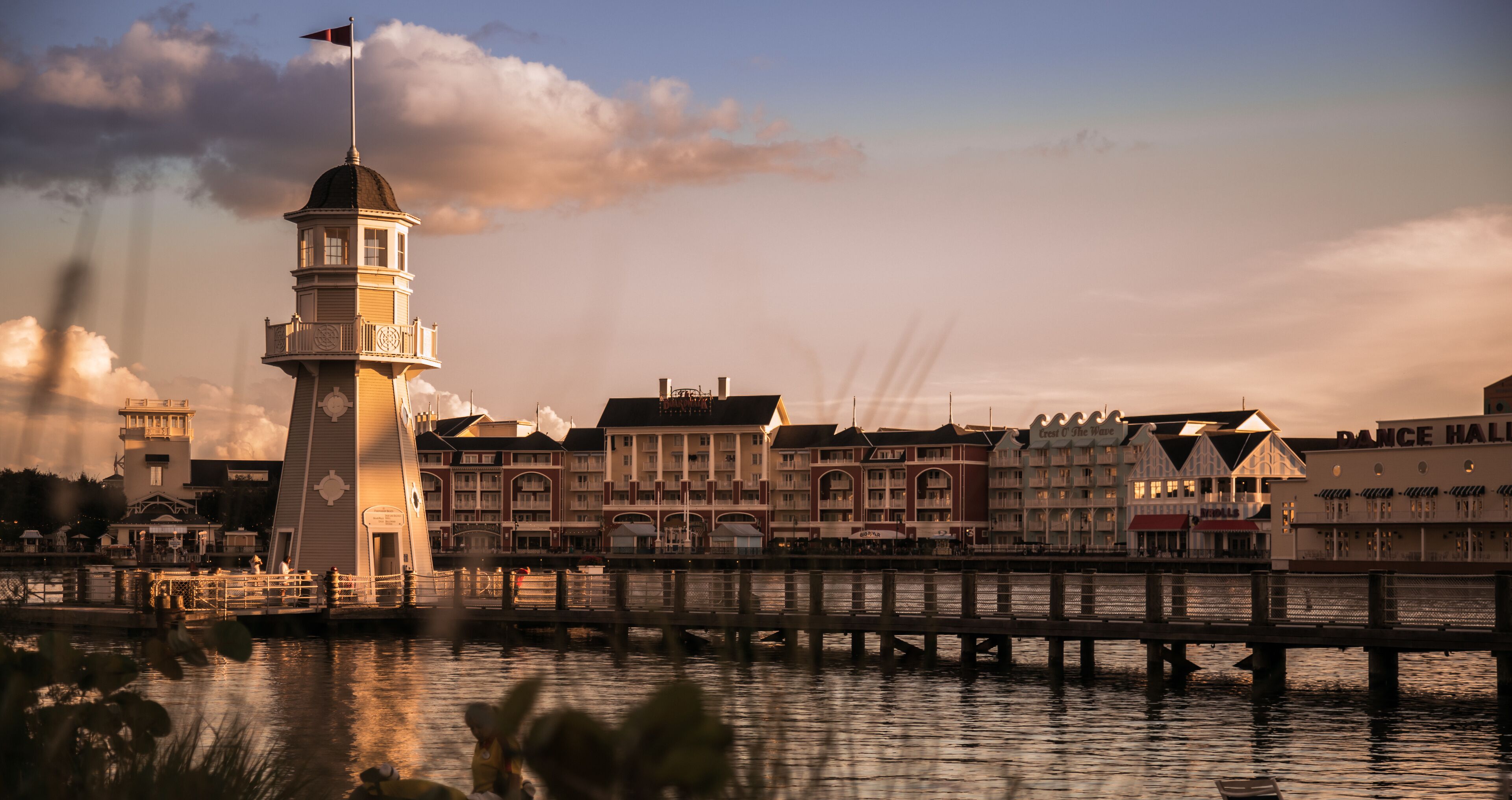 A waterfront with a lighthouse, a pier, and buildings including a hotel and a dance hall.