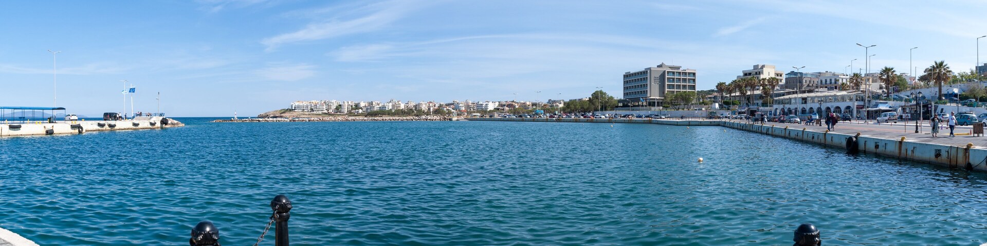 A coastal cityscape with a marina, buildings, and a clear blue sky.