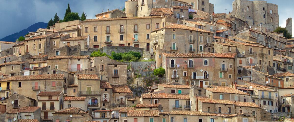 A historic town with terracotta-tiled rooftops, a prominent church with a dome, and a fortified tower.