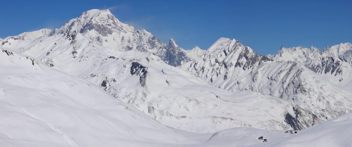 A snow-covered mountain range with sharp peaks and a clear blue sky.