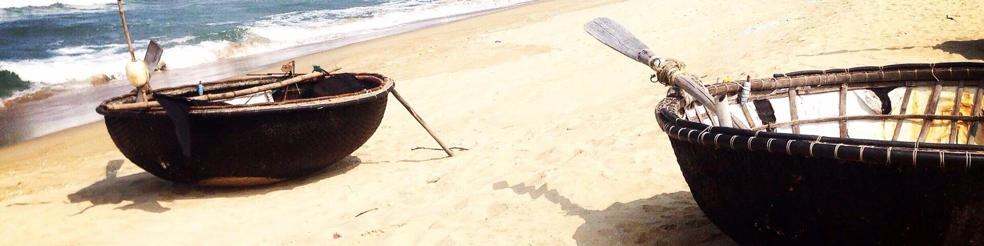 Dos barcos en una playa arenosa con el océano al fondo.