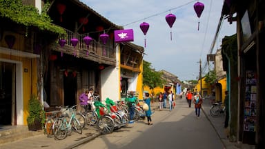 A street with bicycles parked on the side, traditional buildings, and purple lanterns.