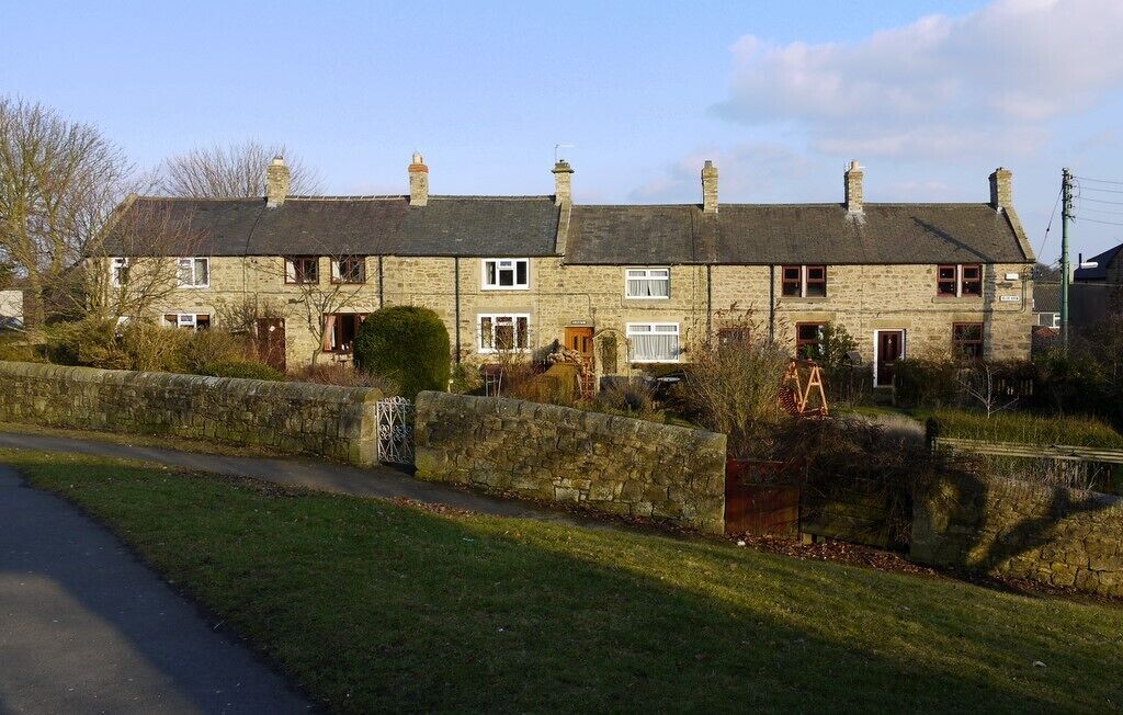 A stone house with a stone wall and a wooden ladder.