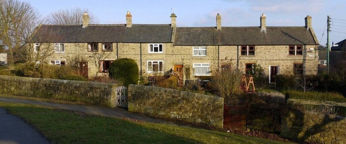 A stone house with a stone wall and a wooden ladder.