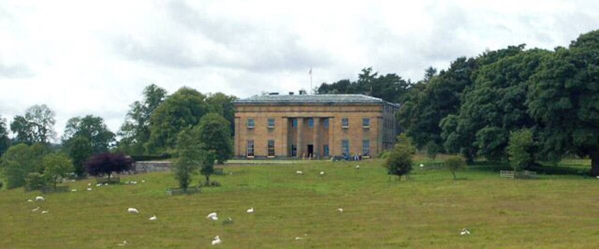 A large brick building surrounded by a grassy field and trees.