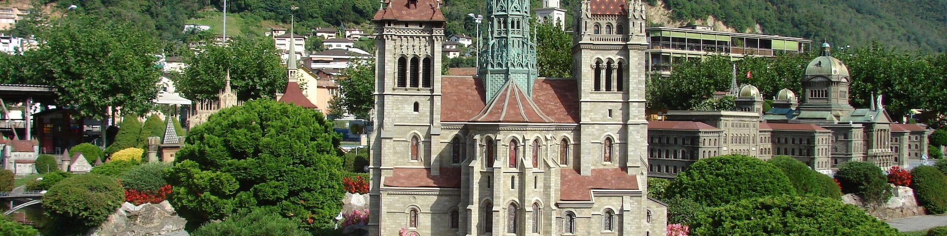 Una iglesia histórica con un campanario alto, rodeada de vegetación exuberante y plantas con flores.