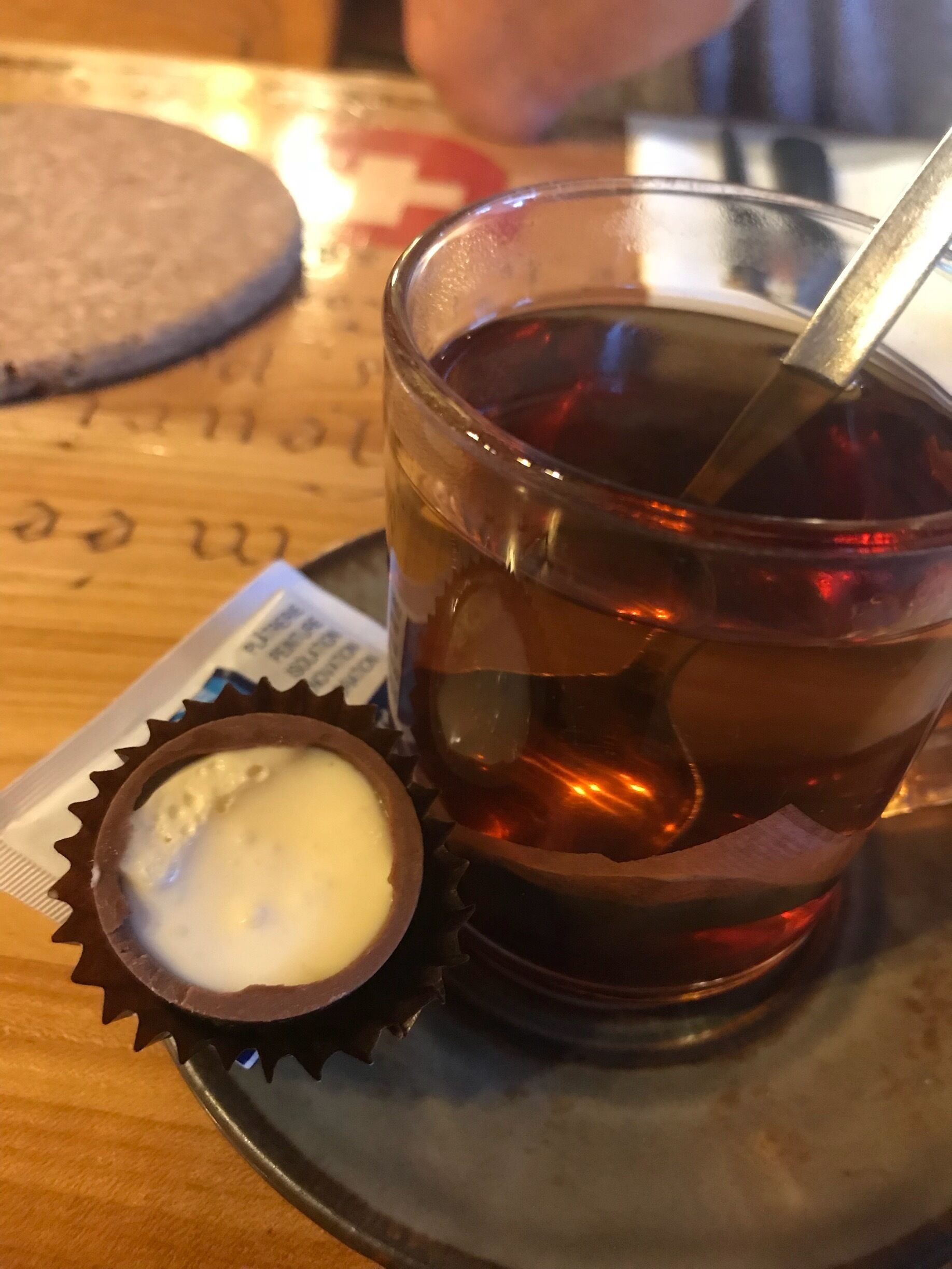 A glass of iced tea with a spoon, a chocolate-covered cookie, and a biscuit on a tray.