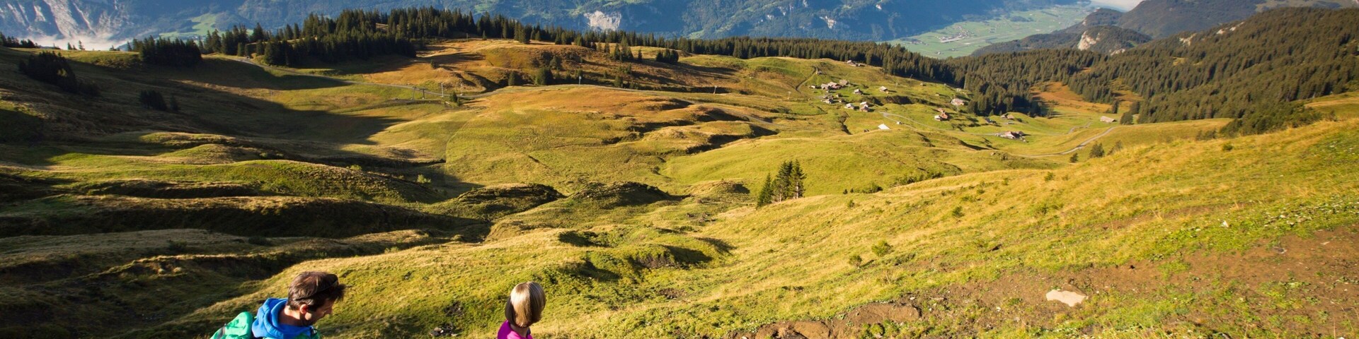 Paisaje montañoso con un valle, casas y cielo despejado.