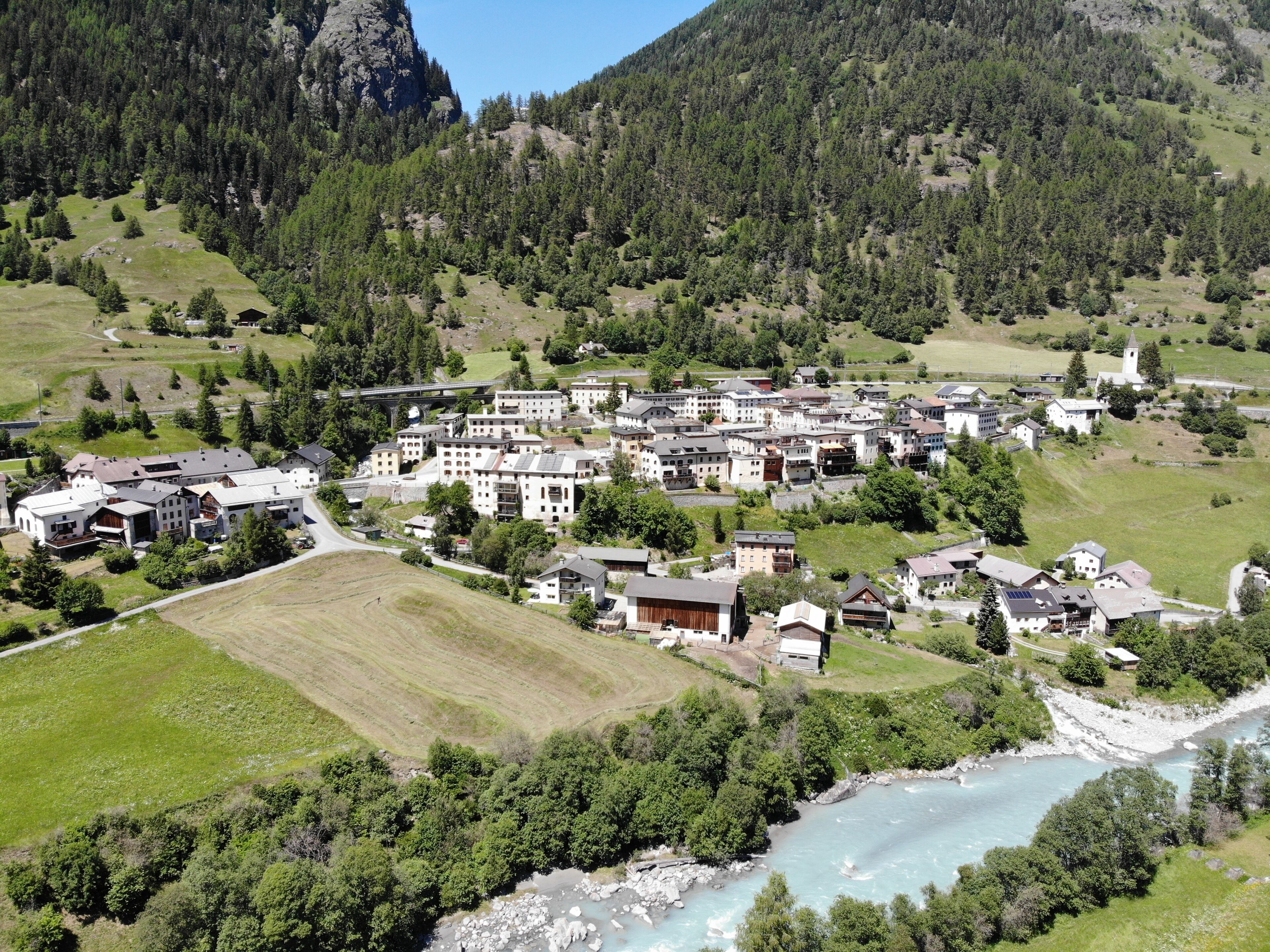 A mountainous village with a river, buildings, and a church.