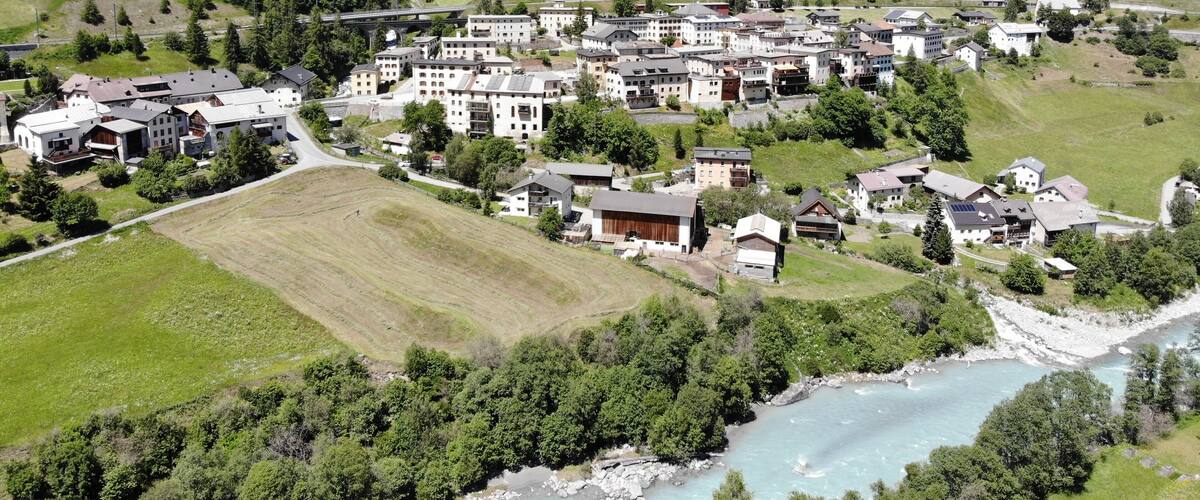 A mountainous village with a river, buildings, and a church.