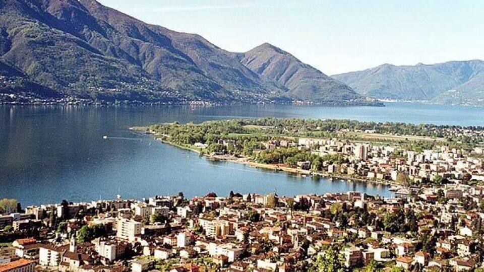 A coastal city with a large body of water, mountains in the background, and dense urban development.