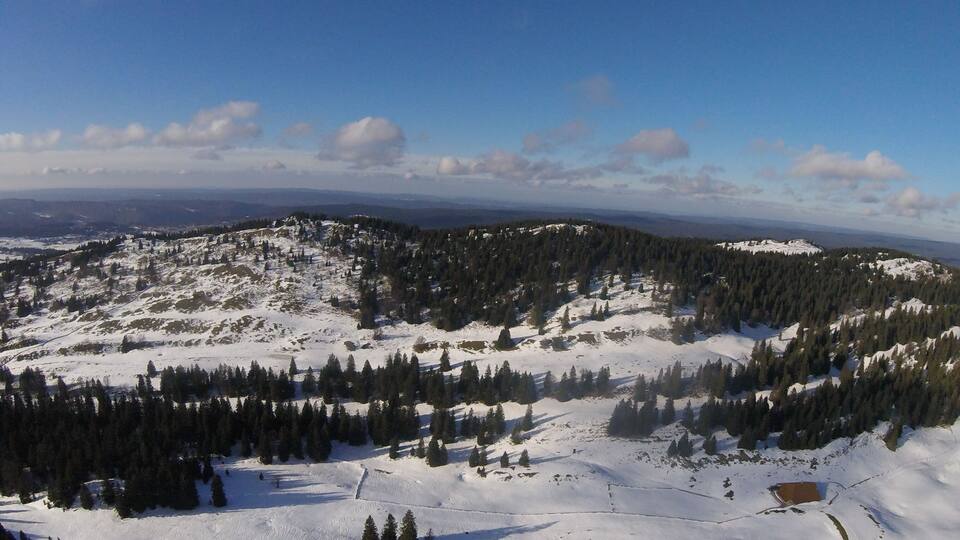 A snow-covered mountain landscape with dense forests and a clear sky.