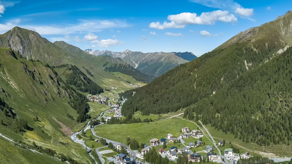 A valley with a river, surrounded by mountains and a small village.