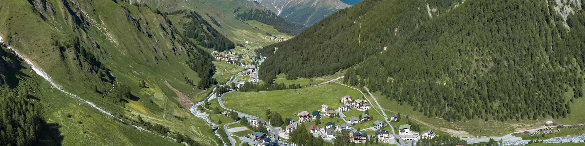 Blick über Samnauen-Dorf, durch das Tal. Links die Berghänge der Samnauen-Gruppe.