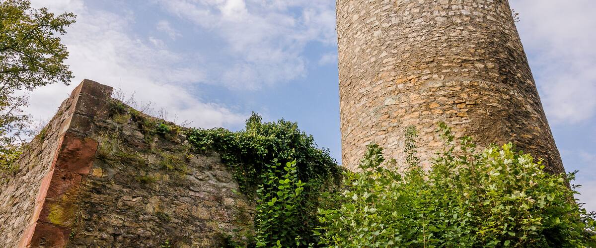 A stone tower with a wooden balcony, surrounded by greenery.
