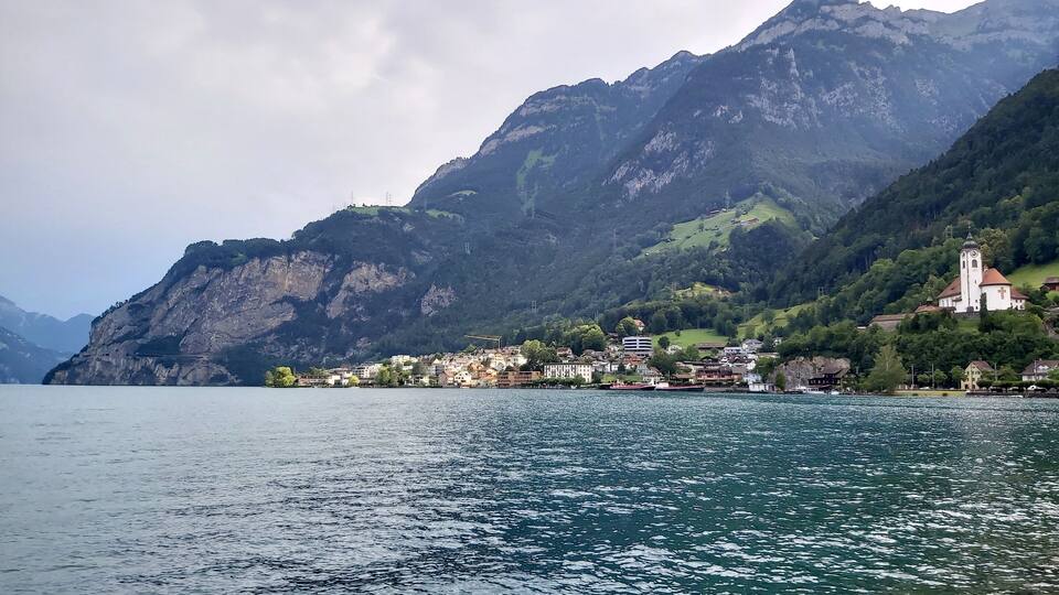 A lake with a mountain in the background and a small town with buildings and a church.