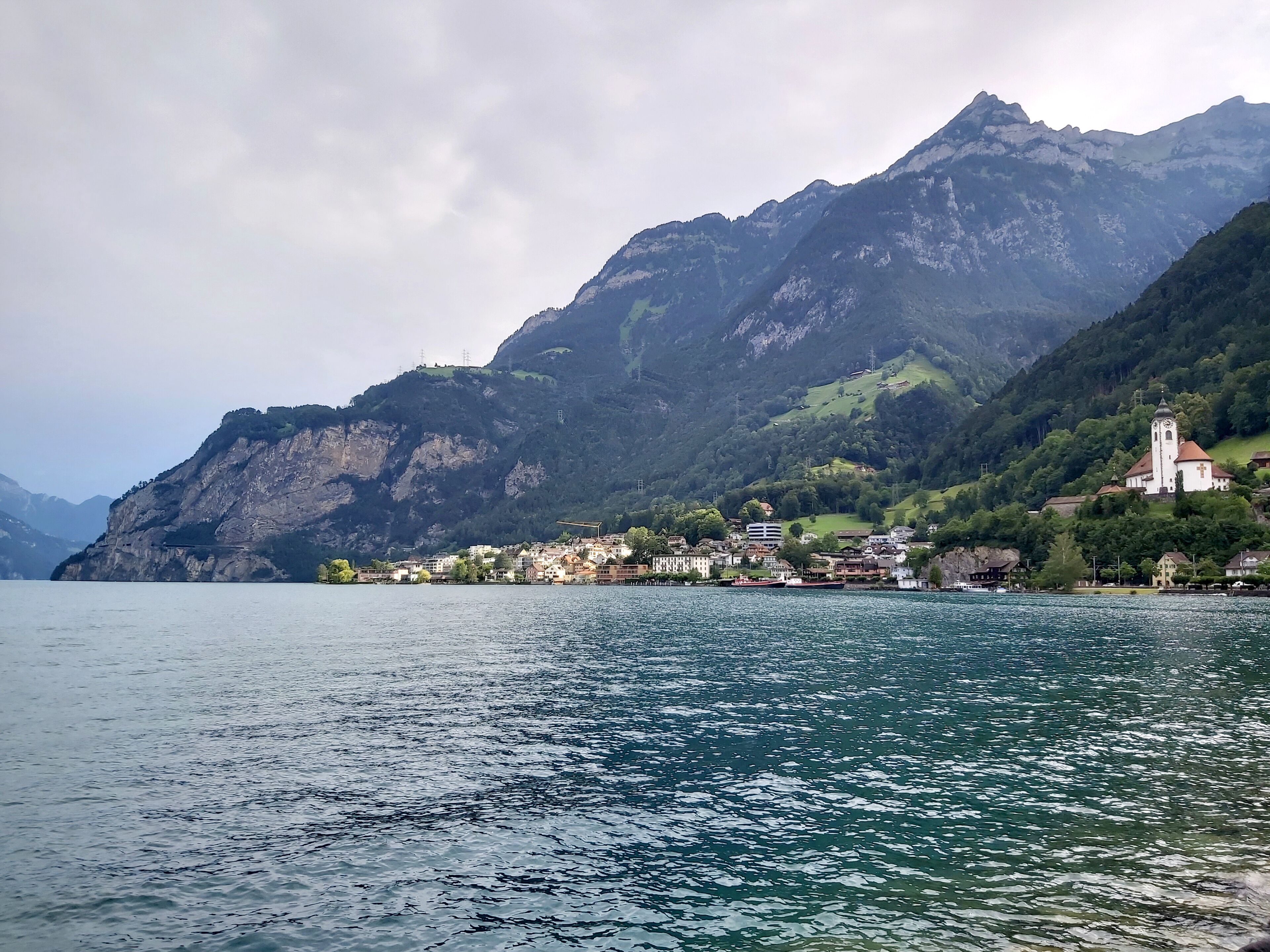 A lake with a mountain in the background and a small town with buildings and a church.