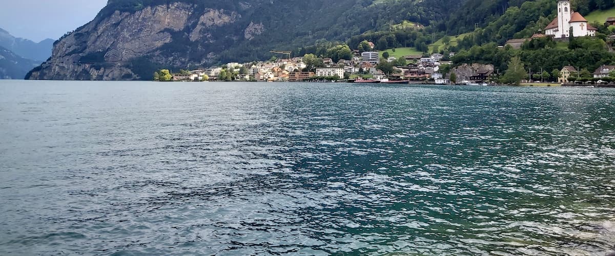 A lake with a mountain in the background and a small town with buildings and a church.
