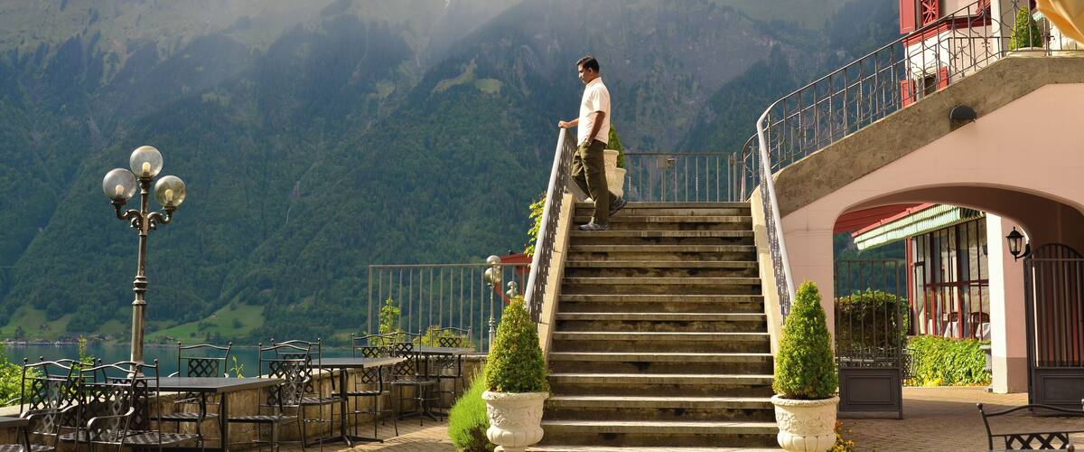 A man descending a stone staircase with a mountainous backdrop.
