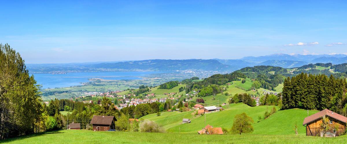 A mountainous landscape with a village, green fields, and a lake.